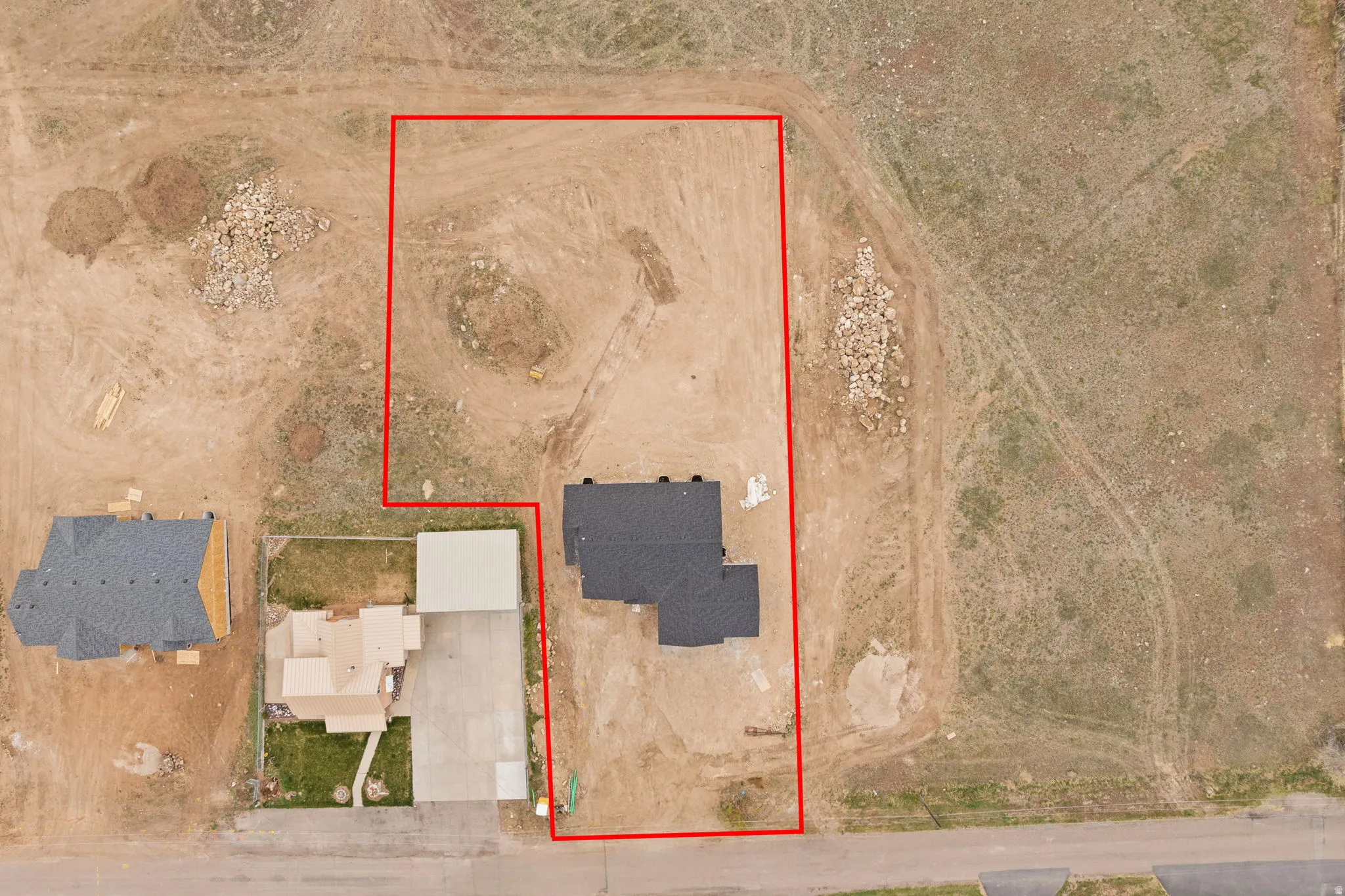 Spacious undeveloped land parcel outlined in red, featuring a partial residential structure with a dark shingle roof