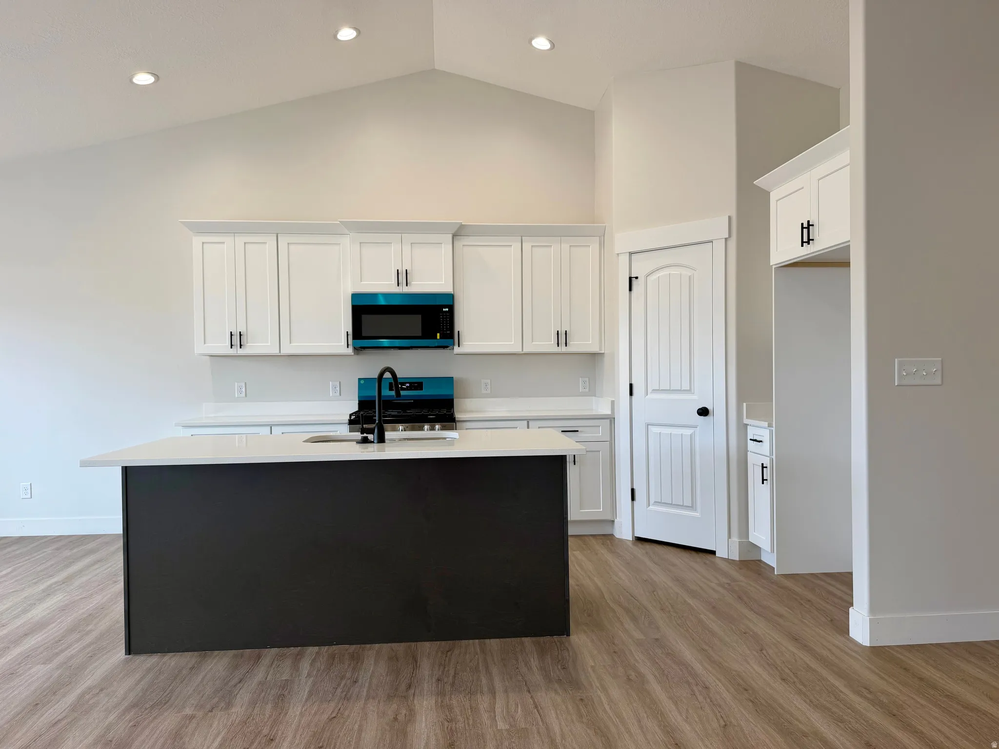 Kitchen with two-tone custom cabinetry with soft-close. Center island sink and dishwasher and stainless steel appliances