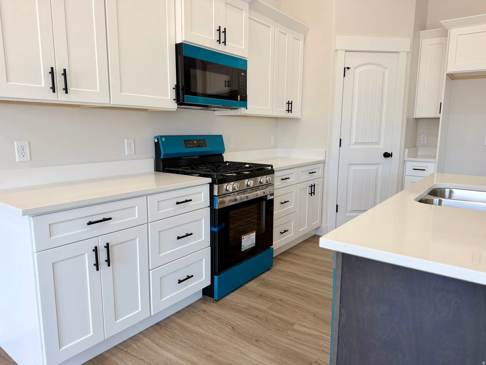 Kitchen with two-tone custom cabinetry with soft-close. Center island sink and dishwasher and stainless steel appliances