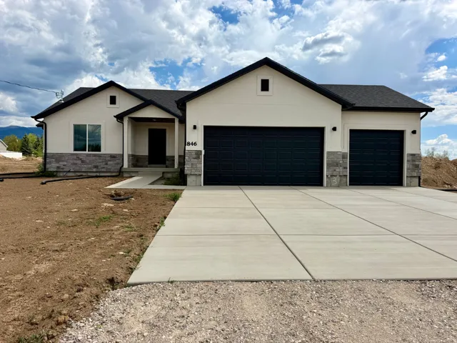 New ranch-style home featuring a cream stucco facade and dark gray stone accents
