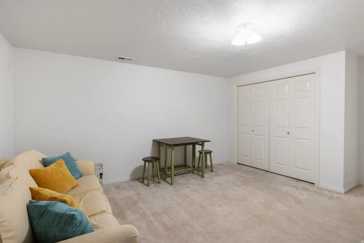 Large bedroom featuring white walls, a built-in closet with bifold doors, and a ceiling-mounted light fixture