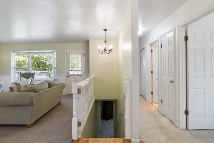Upper-level landing featuring a chandelier, white paneled doors, and a staircase with a white baluster railing