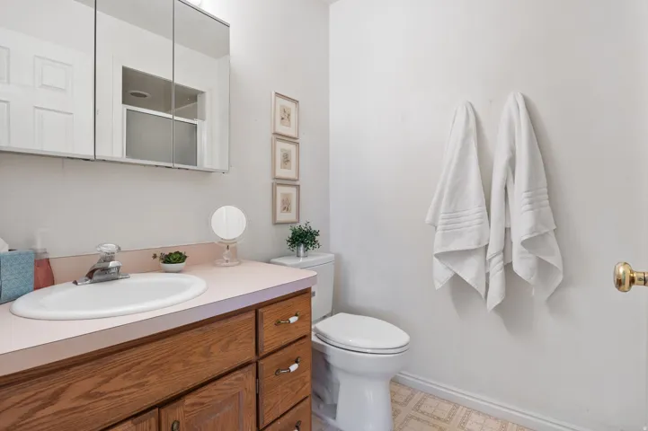 Primary Bathroom featuring a wood-finish vanity with a pink countertop and integrated oval sink