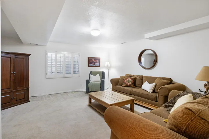 Spacious familyroom featuring light-colored carpeting, white walls, and a window with plantation shutters