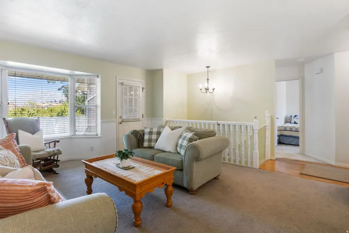 Living area with a prominent bay window, white wainscoting, and a chandelier fixture