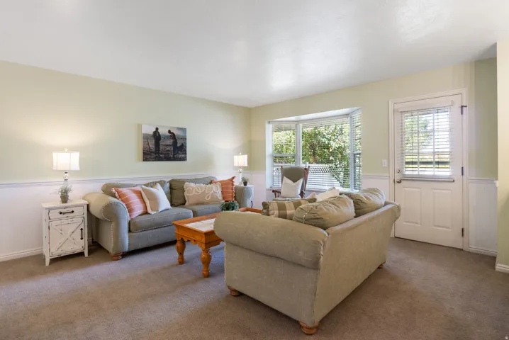 Living area featuring wainscoting, a bay window with blinds, and a rear entry door with blinds
