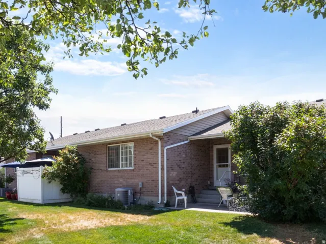 Expansive back lawn and patio with mature trees and a white privacy fence