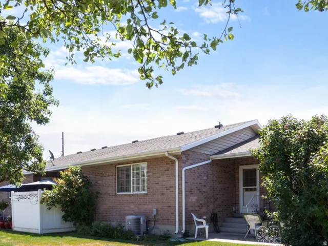 Expansive backyard with a manicured lawn, mature trees, and a white privacy fence