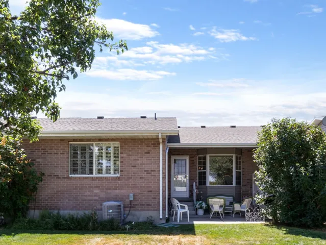 Rear exterior featuring brick siding, a white privacy fence, and a patio area