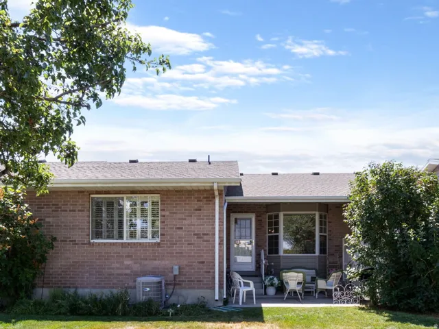 Expansive rear yard featuring a brick exterior, a bay window, a glass-paneled door, a concrete patio, and a white privacy fence