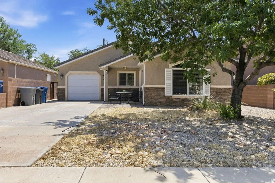 Stucco and stone exterior featuring a single-car garage, concrete driveway, and front entry seating area