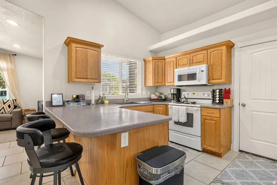 Kitchen featuring oak cabinetry, white appliances, and a peninsula countertop