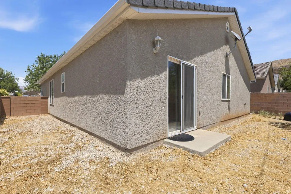 Exterior featuring stucco siding, white window trim, a concrete patio, and a sliding glass door