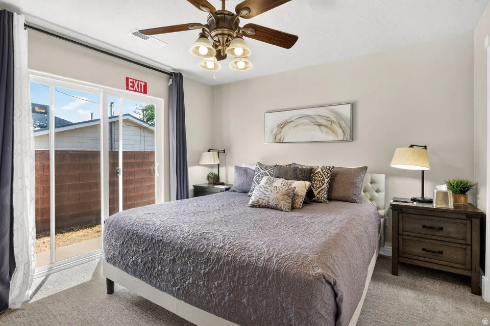 Carpeted room featuring a ceiling fan with integrated lighting, sliding glass door, and neutral wall paint
