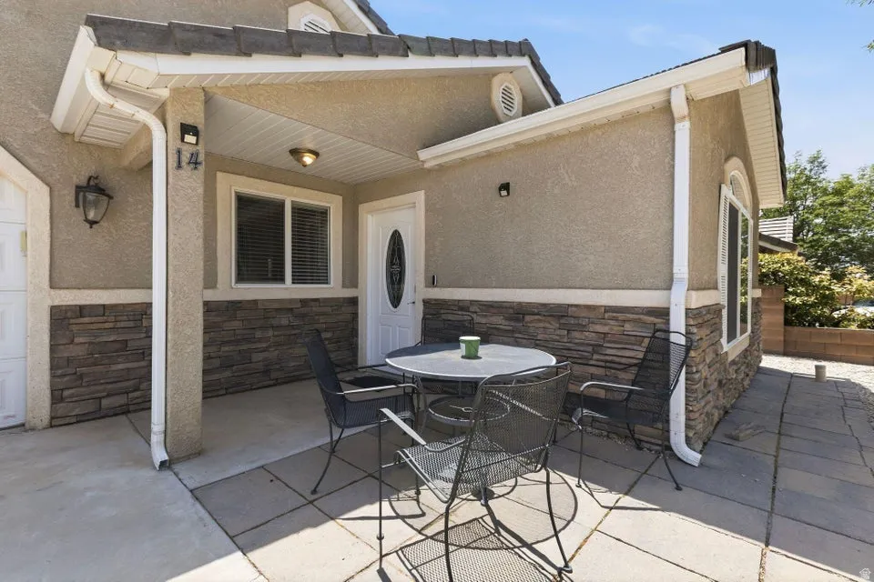 Stucco exterior featuring stacked stone accents and a covered entry