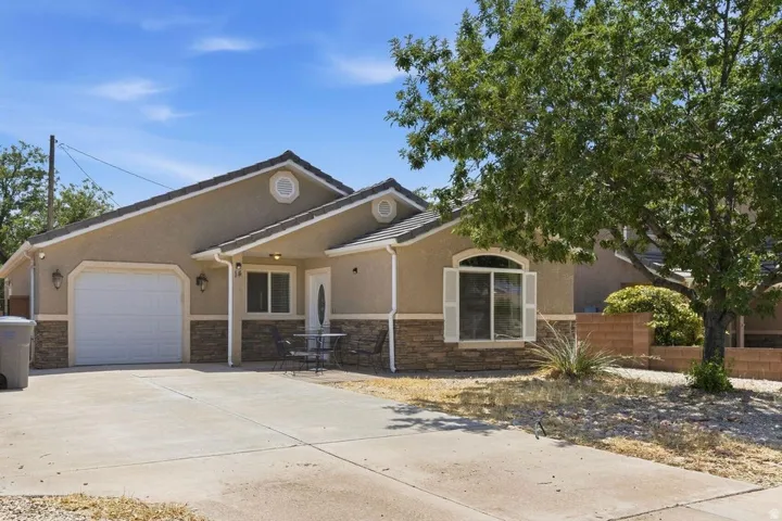 Stucco exterior with stone veneer accents, a prominent arched window, attached garage, and a concrete driveway