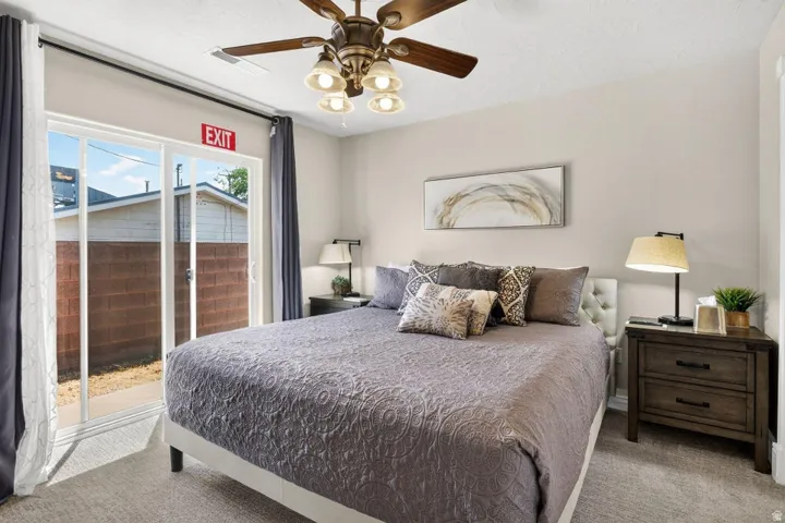 Carpeted room featuring a ceiling fan with integrated lighting, sliding glass door, and neutral wall paint