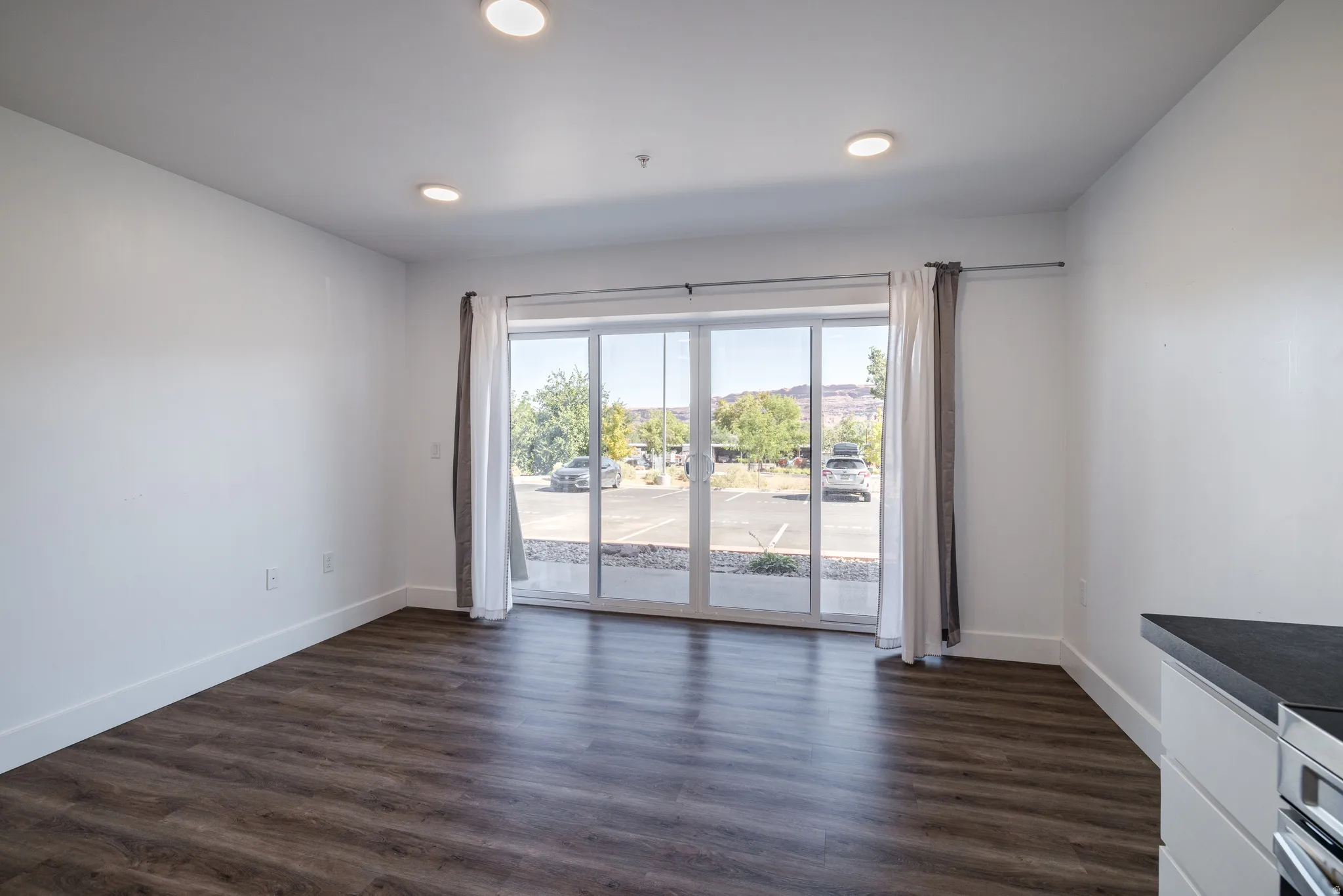 Spacious room featuring wood-finish flooring, white walls, and recessed lighting