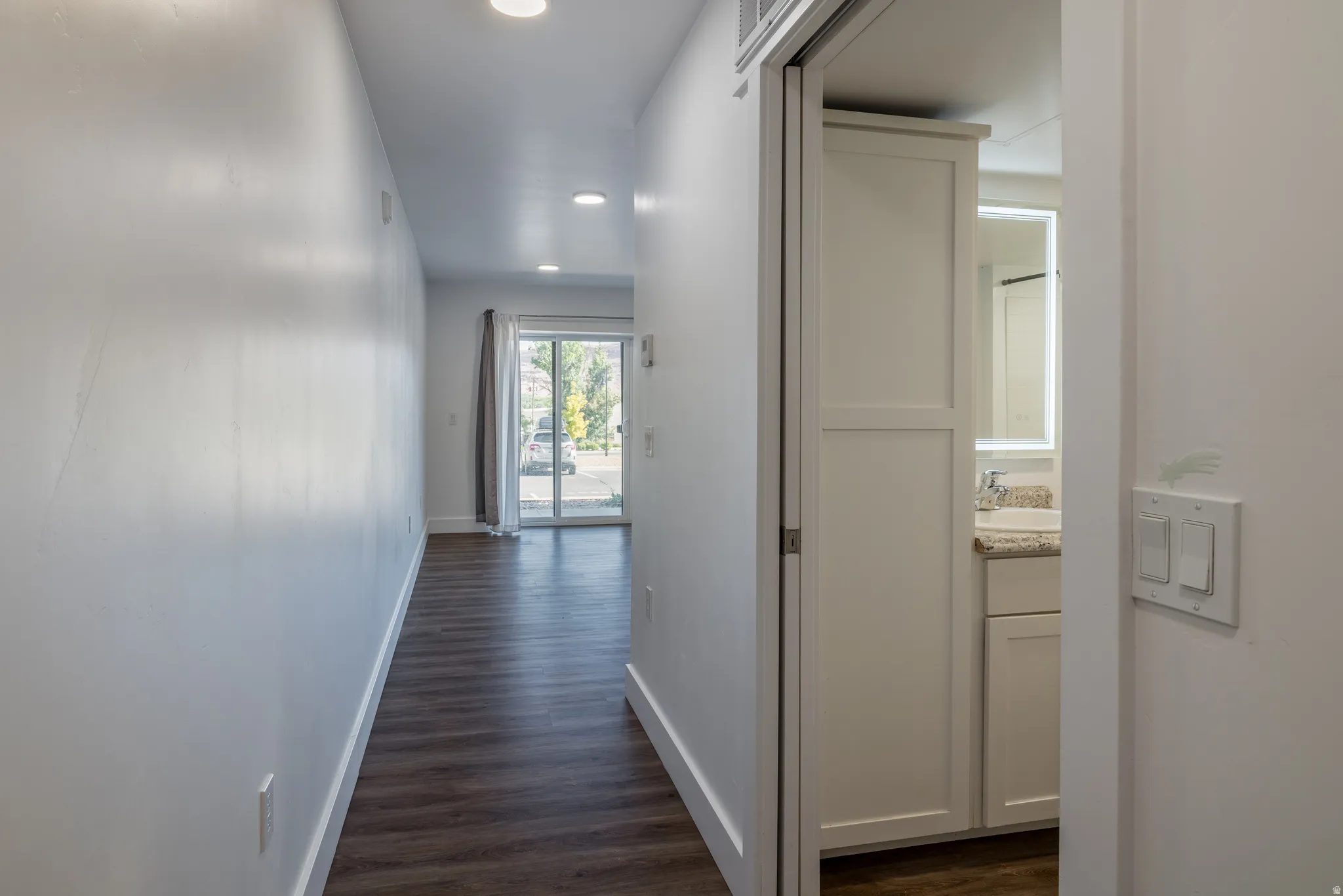 Hallway featuring wood-finish flooring, white baseboards, and recessed ceiling lighting