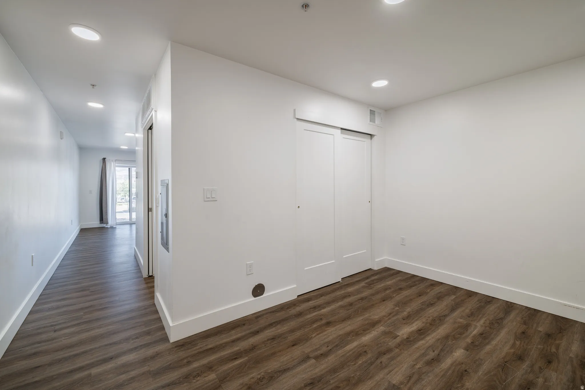 Spacious room featuring wood-finish flooring, recessed lighting, and a sliding door closet