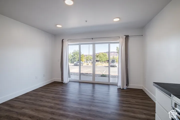 Spacious room featuring wood-finish flooring, white walls, and recessed lighting