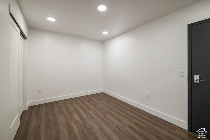 Spacious room featuring wood-finish flooring, recessed lighting, white baseboards, and a sliding barn-style closet door