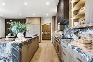 Kitchen featuring a waterfall island, integrated appliances, wood-finish flooring, and open shelving