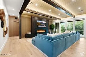 Wood-finish flooring throughout, with a wood-paneled ceiling featuring recessed lighting and dark exposed beams