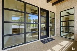 Large format windows, glass paneled door, exposed wood beams, textured exterior walls, and textured flooring