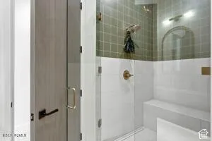 Glass-enclosed shower with a built-in bench, green tiled accent wall, and brass-finish fixtures