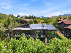 Multi-level modern exterior with expansive windows, a large deck, and a metal roof