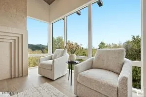 Vaulted ceiling, floor-to-ceiling windows, wood-finish flooring, and a decorative fireplace