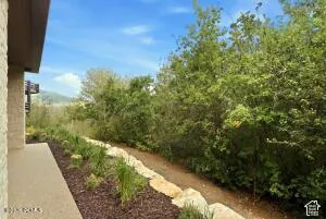 Stone exterior with an outdoor walkway, landscaped garden bed, and a natural tree line