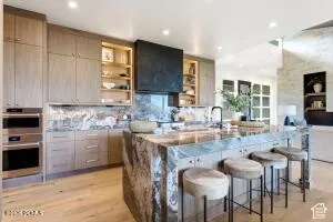 Expansive kitchen island with waterfall countertop, integrated sink, and modern cabinetry with built-in stainless steel appliances
