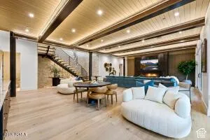 Wood-finish flooring throughout, exposed beam ceiling with integrated lighting, and a stone accent wall
