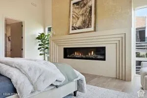 Linear fireplace with a decorative surround, high ceilings, and light wood-finish flooring