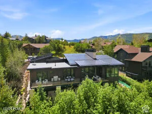 Modern exterior with dark siding, expansive decking, integrated solar panels, and a metal roof