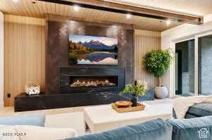 Contemporary fireplace with black stone surround and hearth, featuring a wood-paneled accent wall, wood-slat ceiling, and recessed lighting