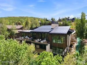 Multi-level modern exterior with a dark metal roof, extensive window walls, and multiple outdoor deck spaces
