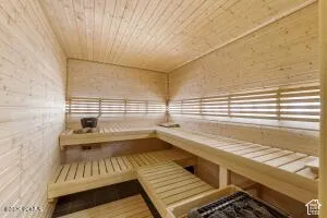 Wood-paneled sauna featuring tiered wooden benches, wood-slat wall accents, wood-finish flooring, and a built-in heater