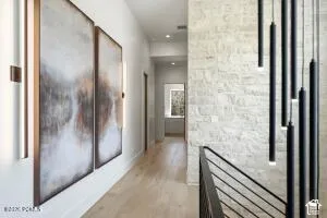 Light wood-finish flooring, white painted walls, and an accent wall with stone-look cladding