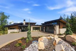 Modern architecture featuring a two-car garage with frosted glass doors, a stone facade, and extensive natural wood accents