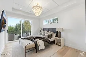 Recessed tray ceiling with coffered detail, wood-finish flooring, sliding glass door access to an outdoor patio, and a contemporary ceiling light fixture