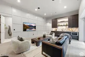 Recessed lighting, wood-finish flooring, custom wall paneling, built-in wet bar with under-cabinet lighting, and integrated beverage cooler