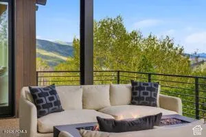 Outdoor living area featuring a built-in fire pit, metal railing, wood-paneled wall, and expansive mountain scenery