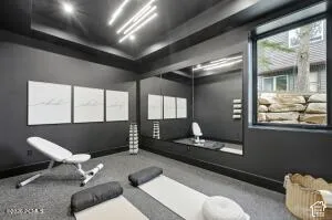 Recessed and linear ceiling lighting, full-wall mirror, and a large window with a stone retaining wall