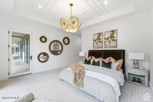 Tray ceiling with recessed lighting, decorative chandelier, white walls, and a glass-paneled door