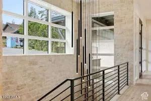 Stone-clad interior walls, multi-paned windows, contemporary pendant lighting, and a modern metal stair railing