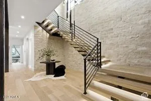 Hardwood flooring, stone accent wall, recessed lighting, floating staircase with metal railing