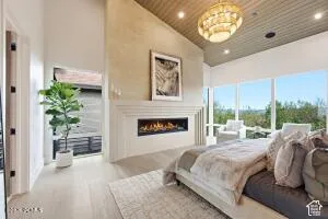 Vaulted ceiling with wood-finish paneling, linear fireplace, full-height windows, recessed lighting, and a decorative chandelier